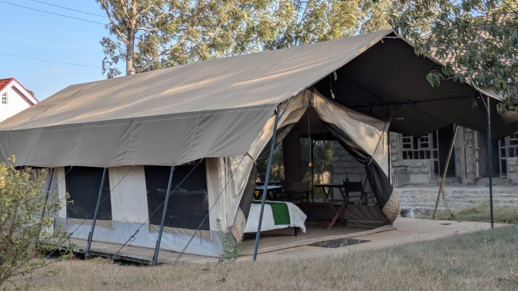 Safari tent porch under canvas with beds and chairs beyond